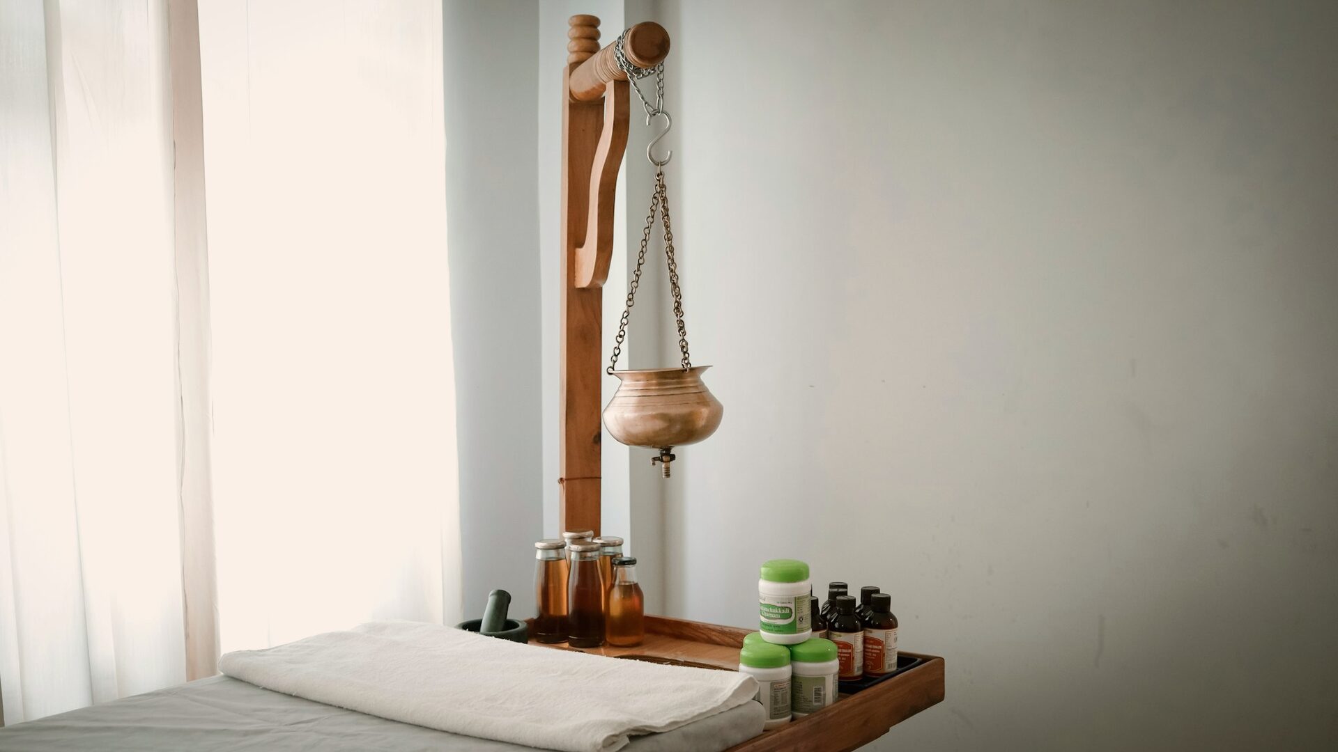 A traditional Shirodhara vessel and herbal oils in the treatment room
