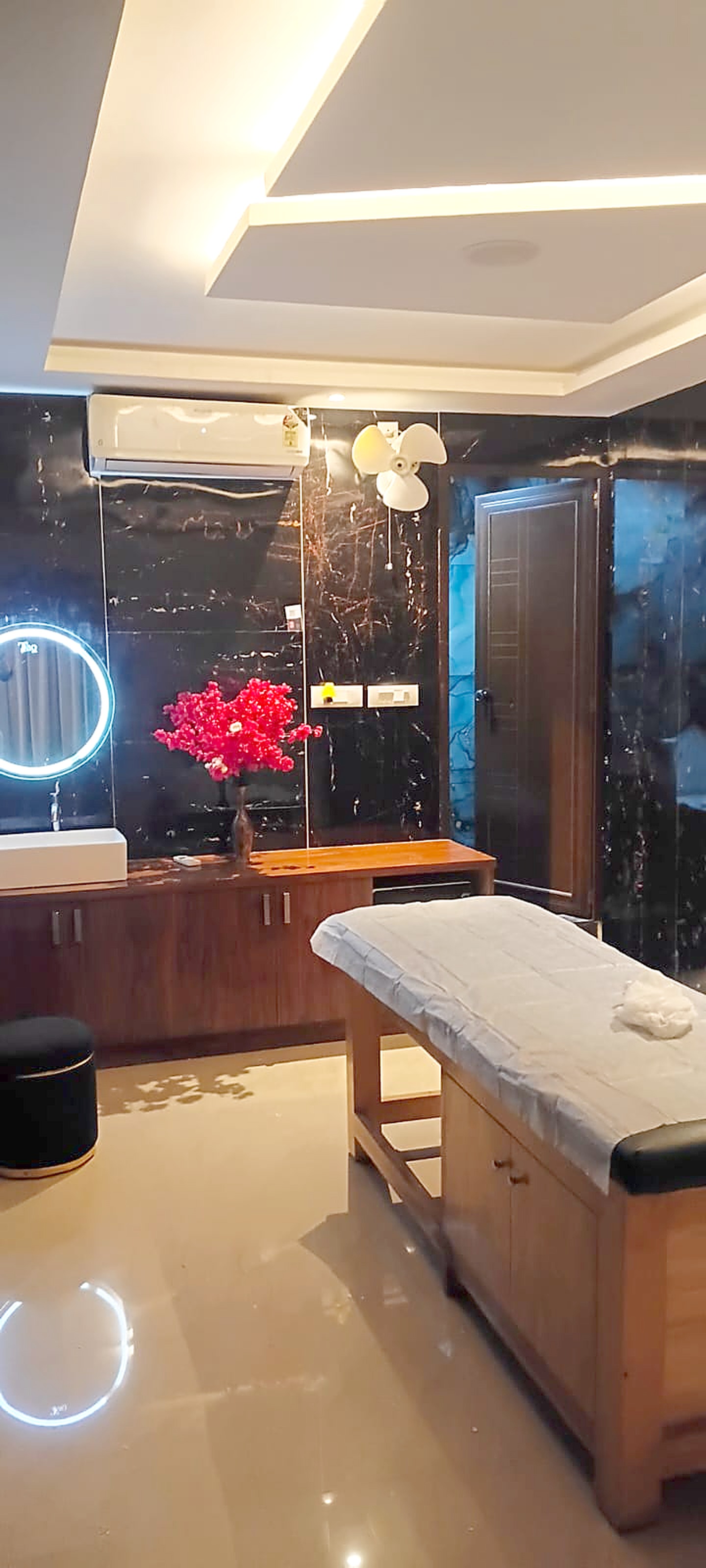 A marble-lined treatment room with a dressed massage table