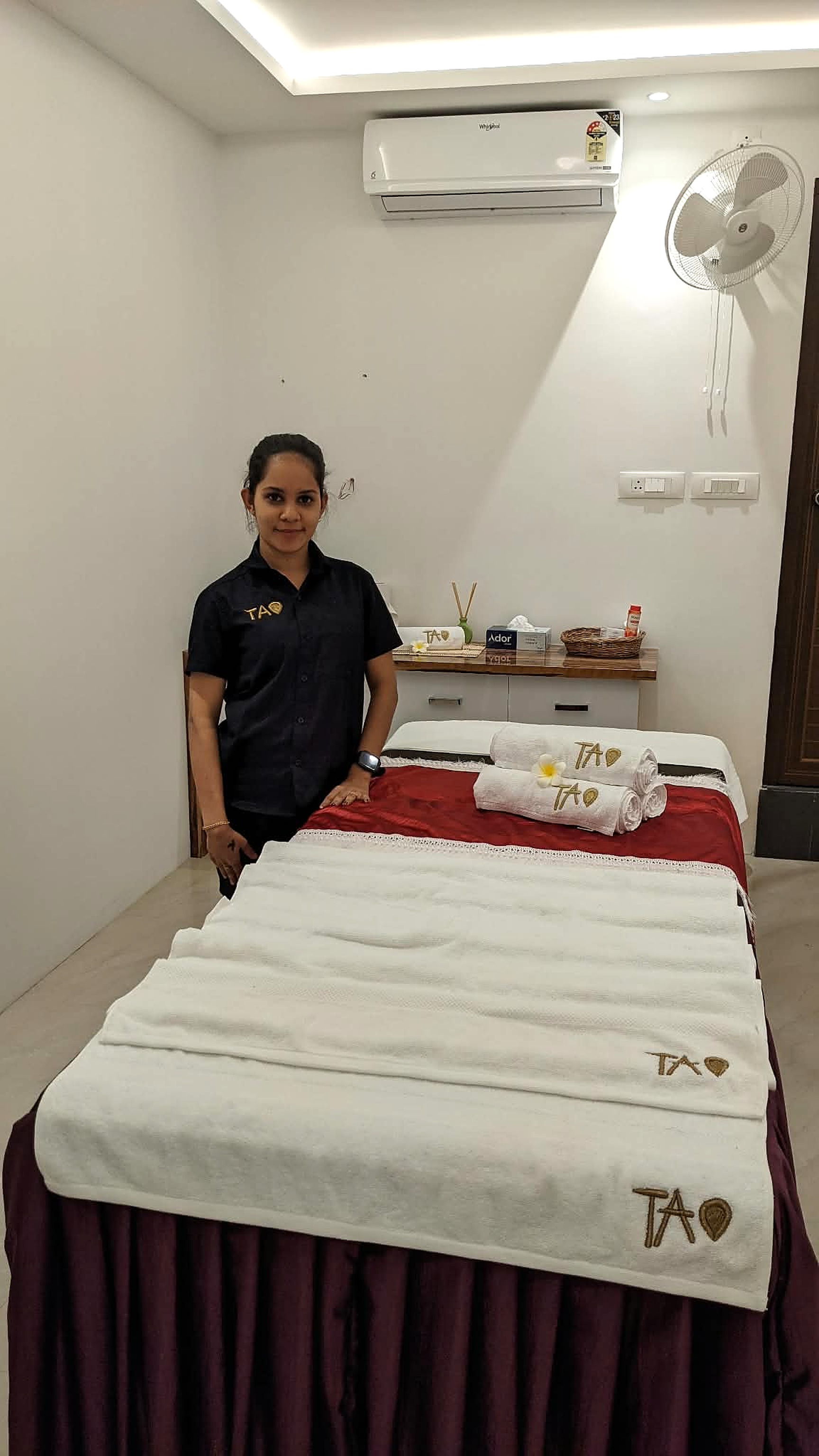 A Tao therapist beside a treatment table dressed with fresh Tao linen